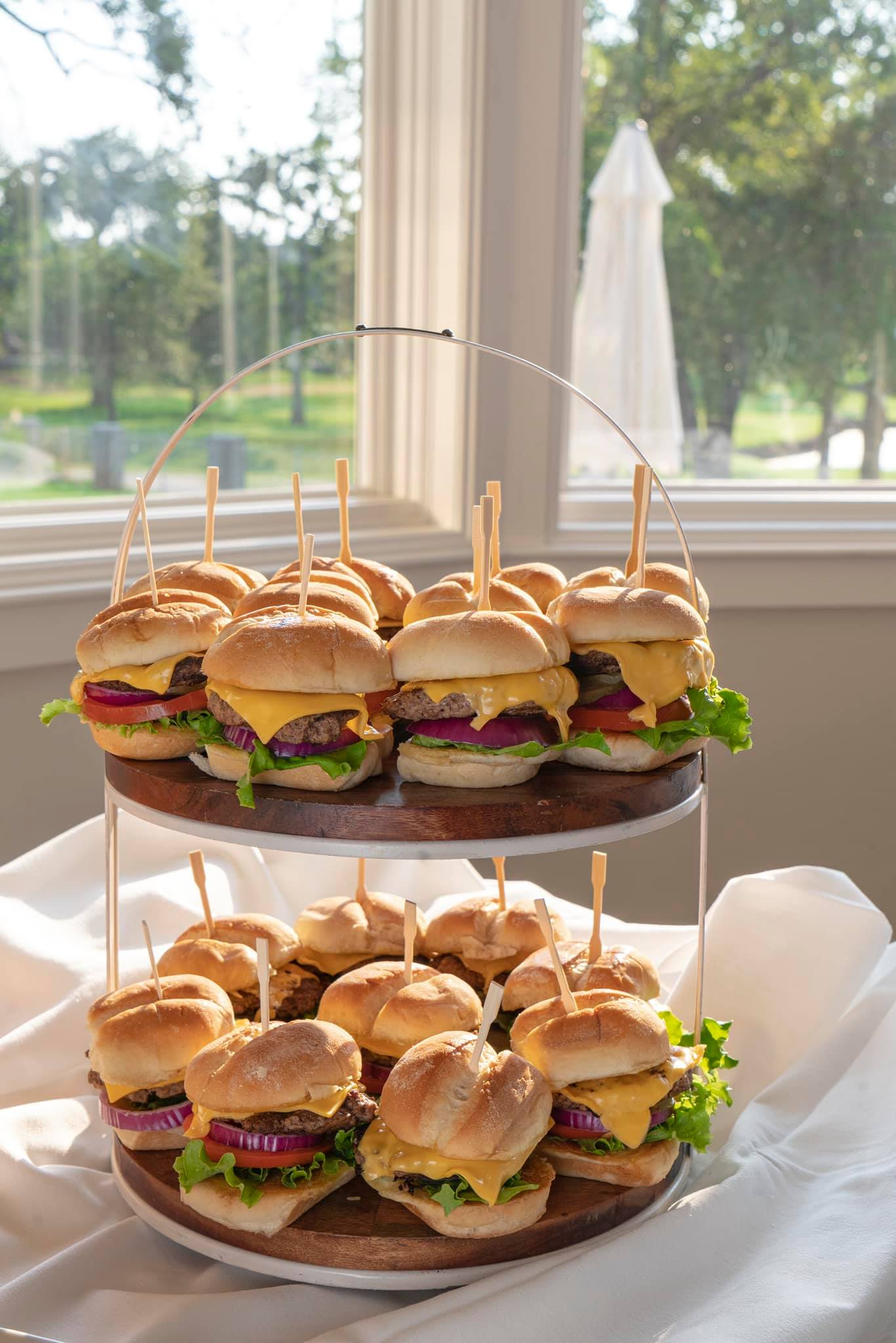 A two-tiered platter of cheeseburger sliders prepared for a catered event